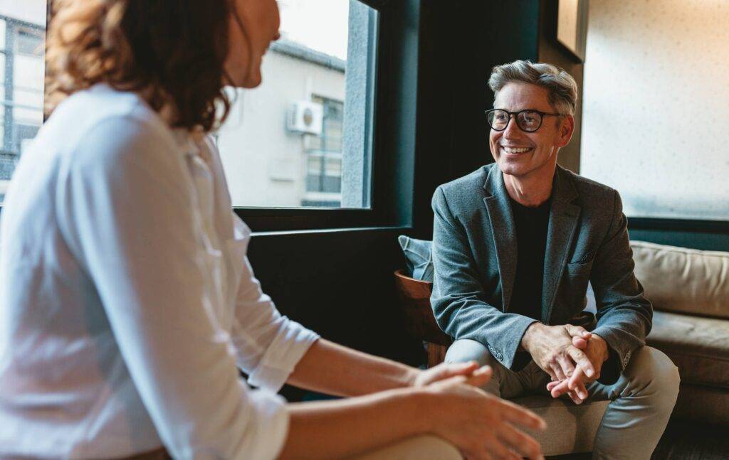 Two business people discussing in office lobby. Businessman talking with female colleague in office.